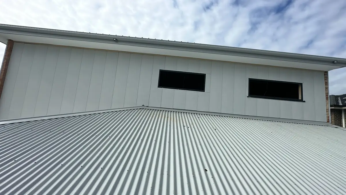 Light-coloured vertical cladding wall above a corrugated metal roof